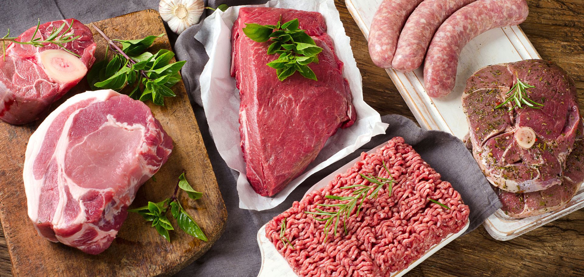 Assorted raw meats and sausages on a dark slate board, garnished with parsley. Assorted raw meats and sausages on a dark slate board, garnished with parsley.