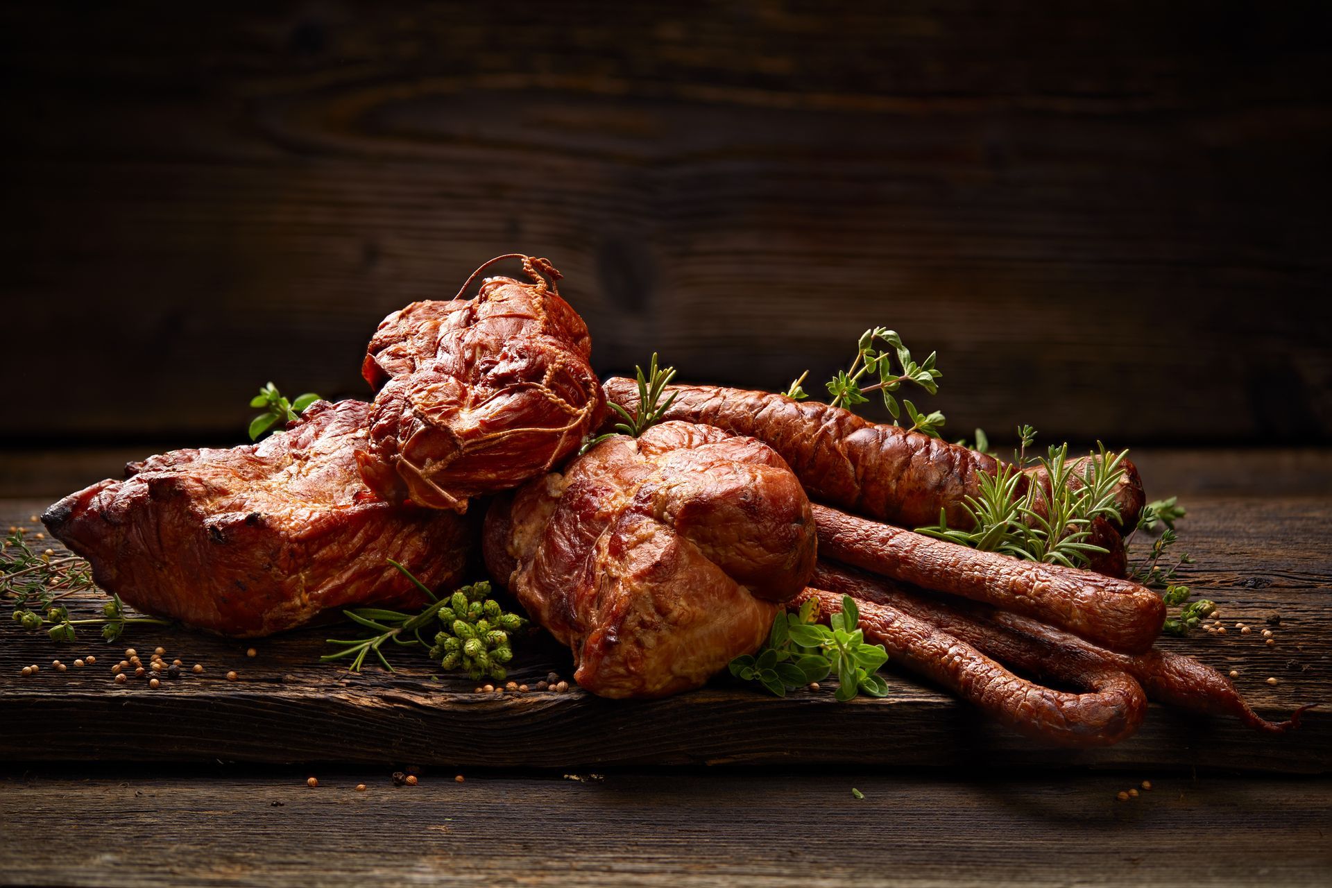 Grilled meat skewers on a wooden board with herbs, lit by warm dramatic light