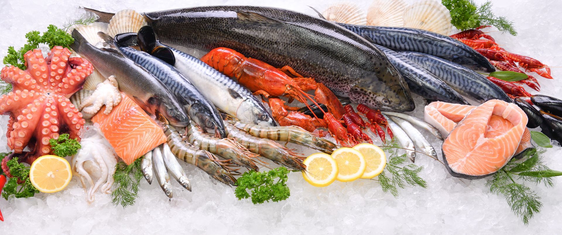 Assorted fresh seafood on ice with lemon wedges, parsley, salmon, octopus, and whole fish