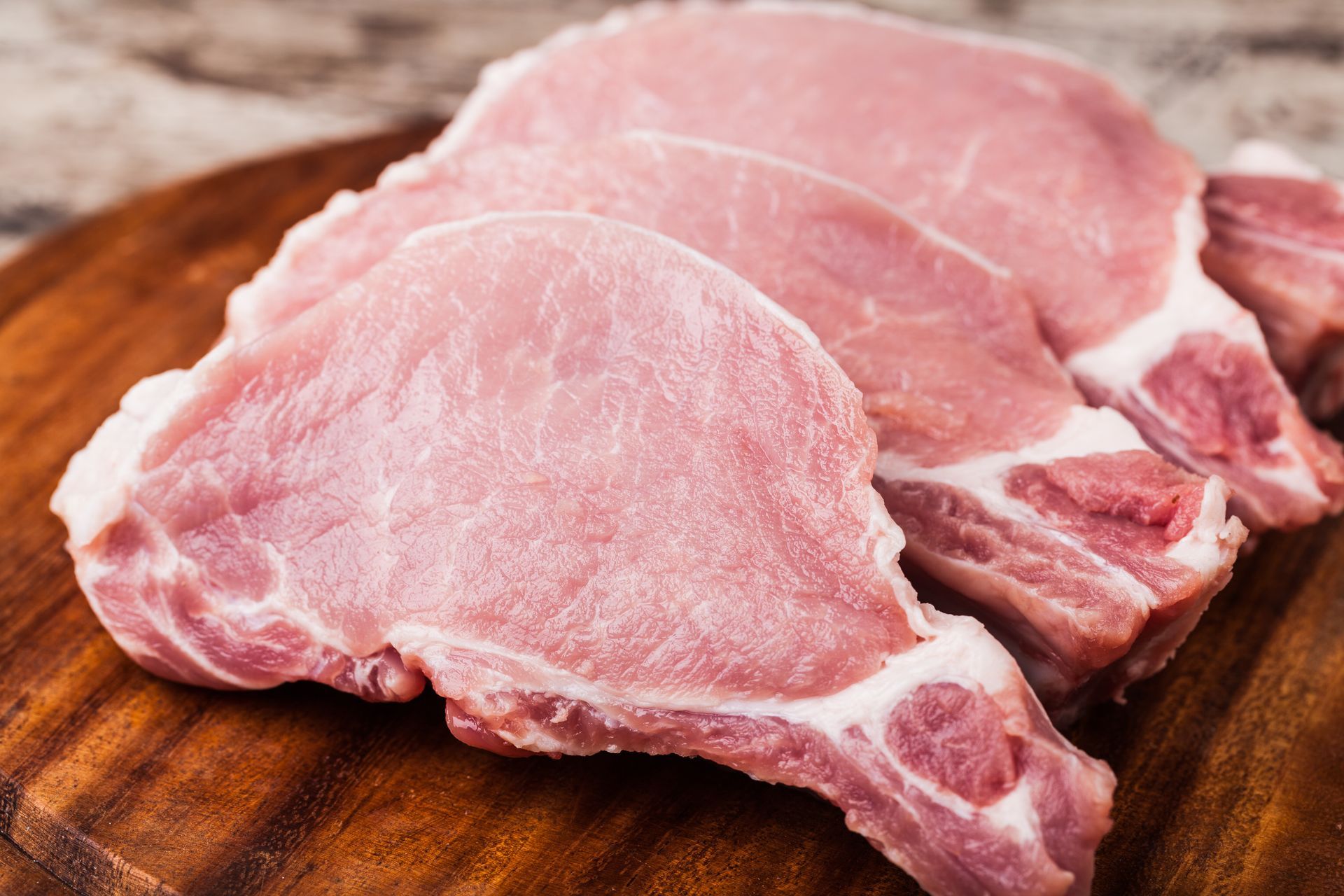 Raw pork chops on a wooden cutting board Raw pork chops on a wooden cutting board