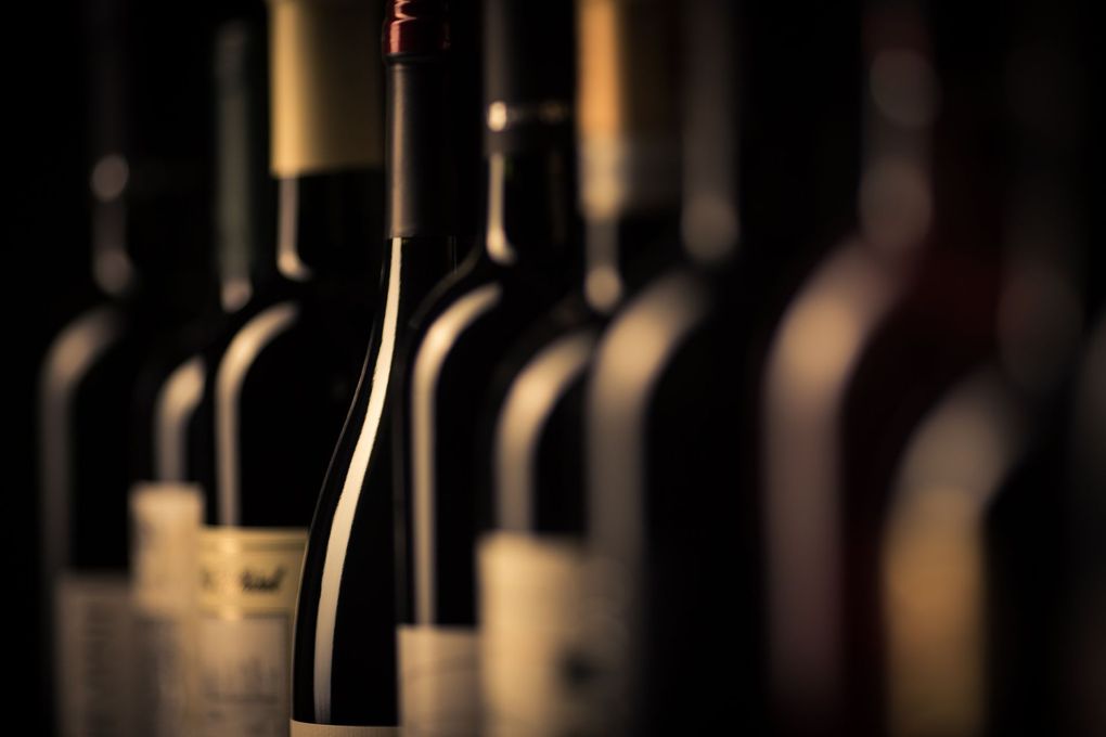 Row of wine bottles in a dark, softly lit cellar or display.