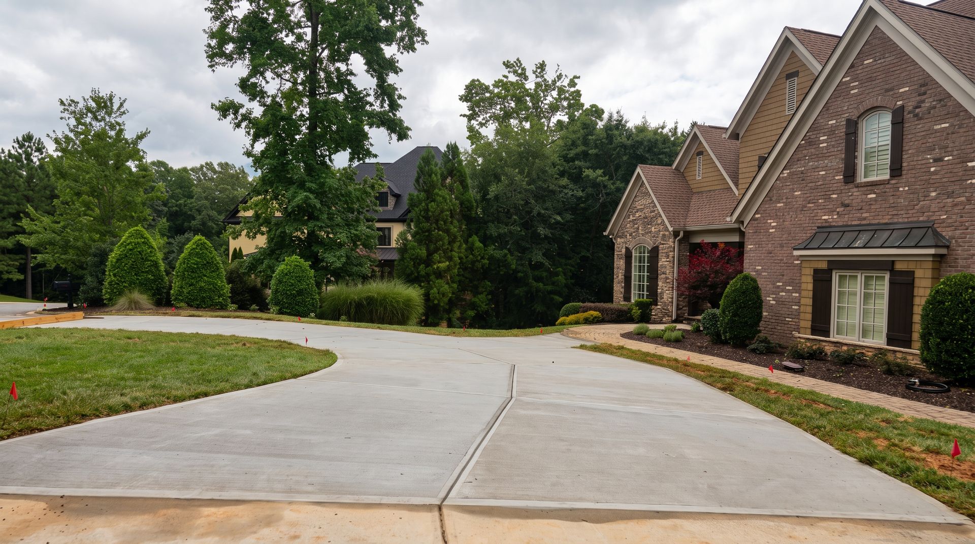 Concrete driveway leading to a white garage with a curved edge and brick house exterior