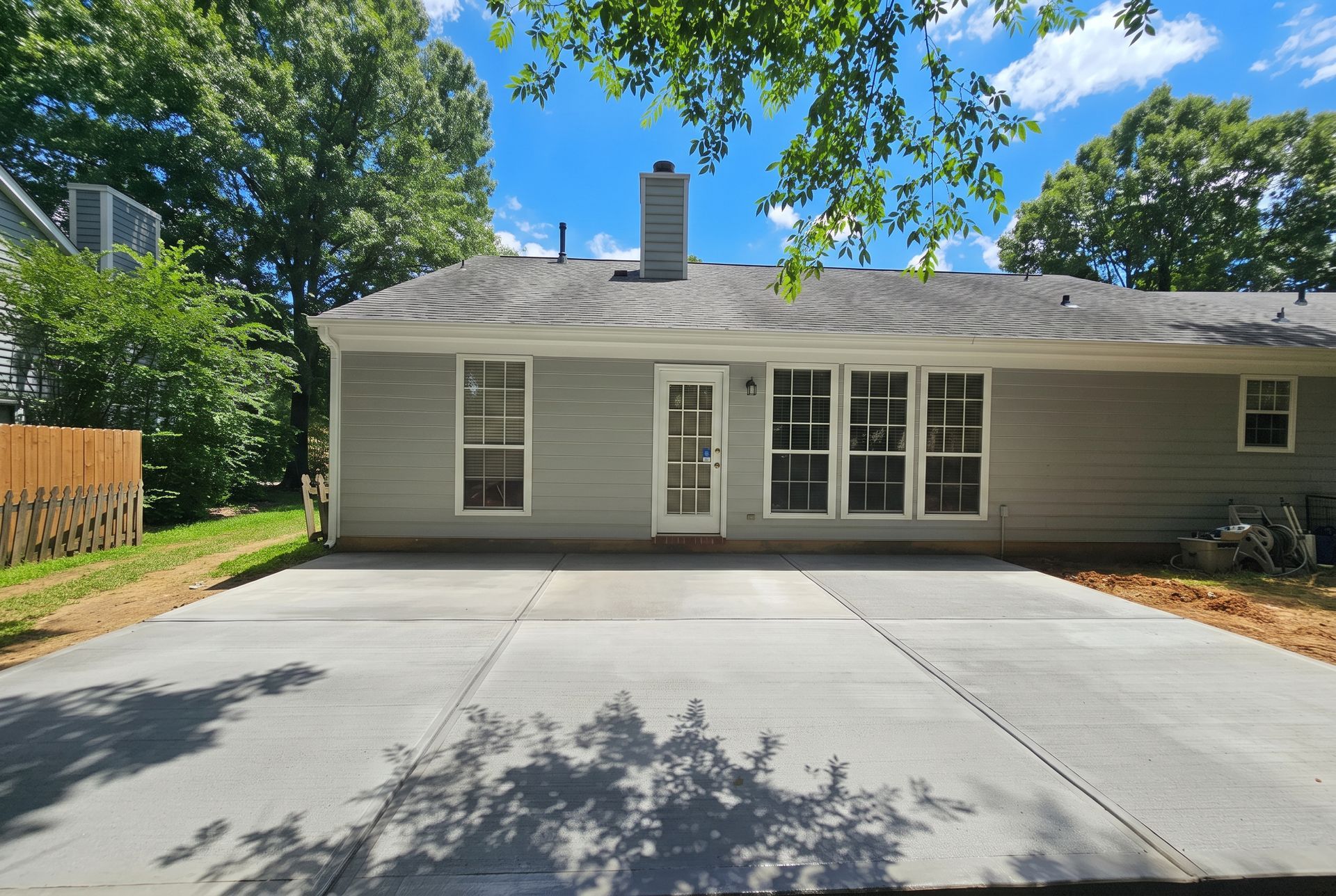 Back porch with screen and white door, green siding, and a large curved concrete patio in a grassy yard