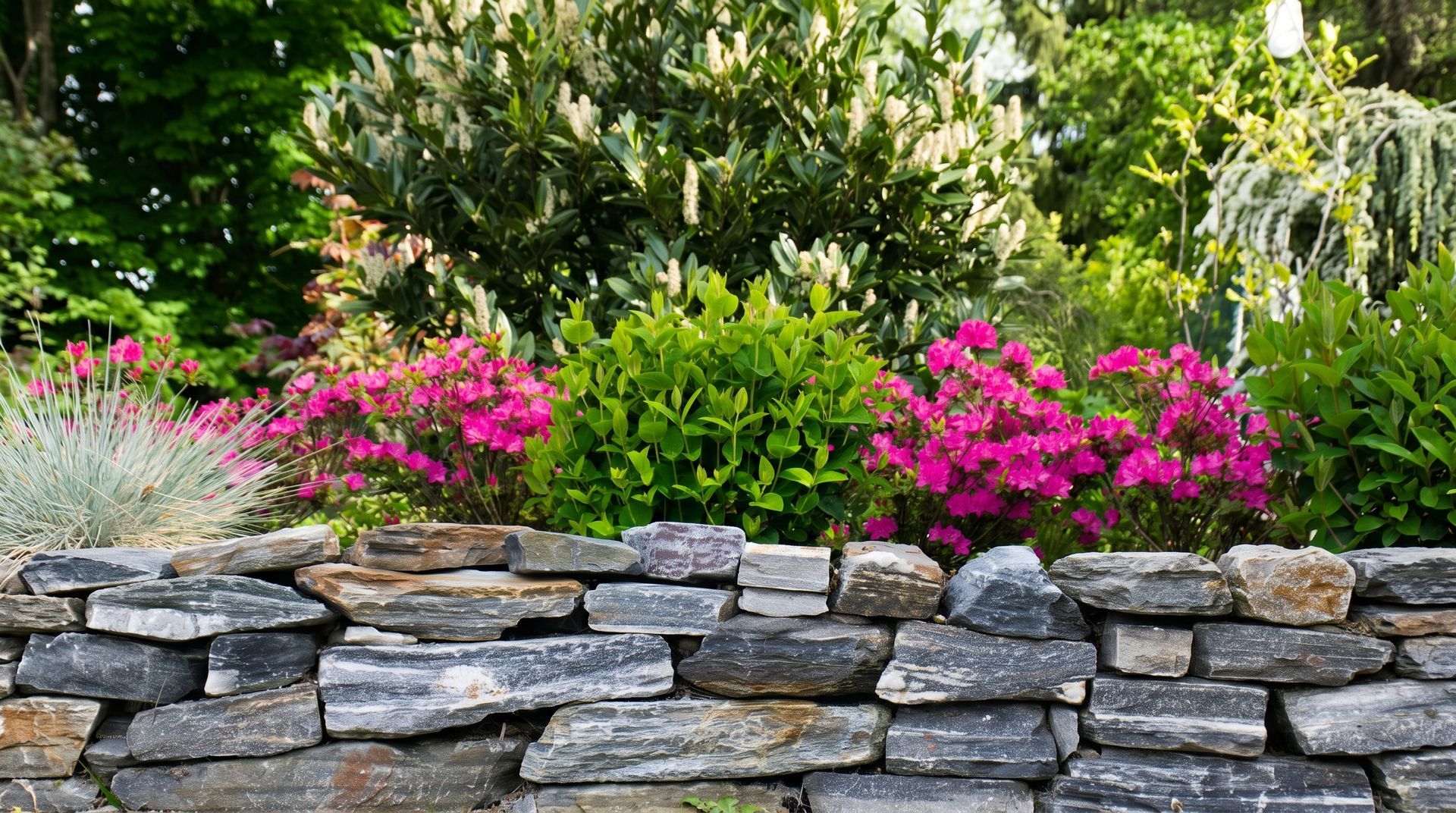 White concrete retaining walls beside a dirt path with shrubs and trees on a sunny hillside