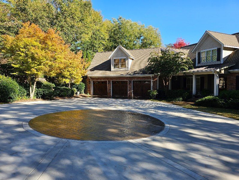 Suburban house with autumn trees and a circular brick driveway in front of the garage