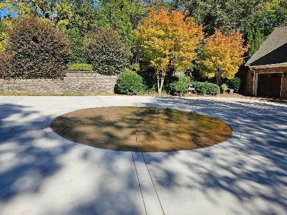 Driveway with a circular stained area in the center, bordered by autumn trees and a garage.