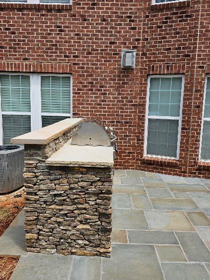 Brick courtyard with stone-topped wall and slate patio beside a house exterior.