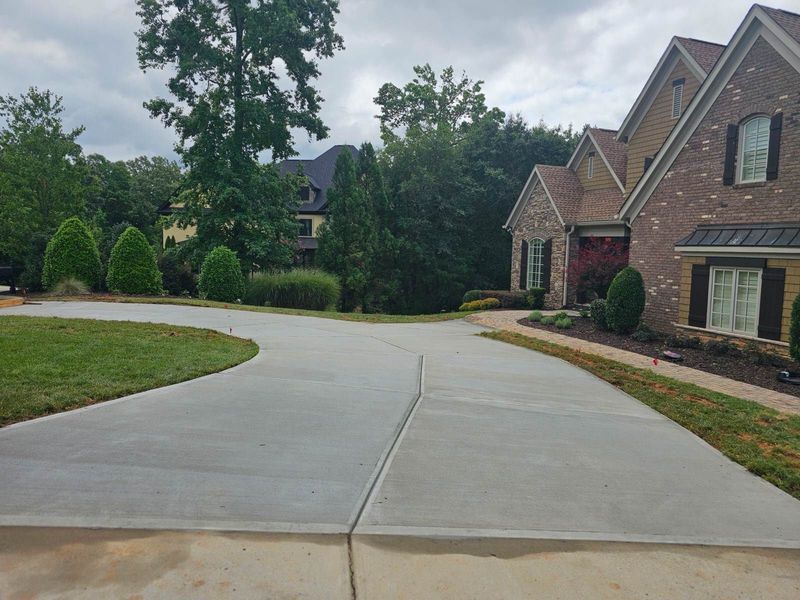 Suburban driveway leading to brick houses and landscaped lawns on a cloudy day