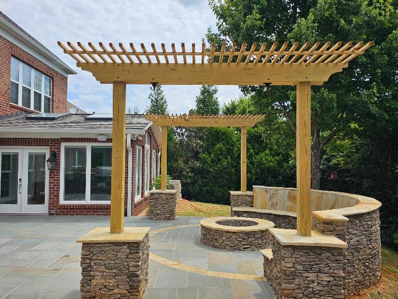 Stone patio with curved seating and wooden pergolas outside a brick building