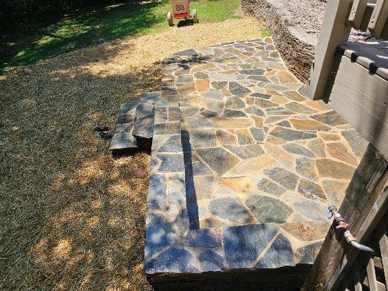 Stone patio walkway beside a grassy yard, with a blue-gray flagstone pattern and curved edge