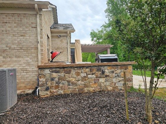 Stone courtyard wall with a red bird perched beside a house and tree.