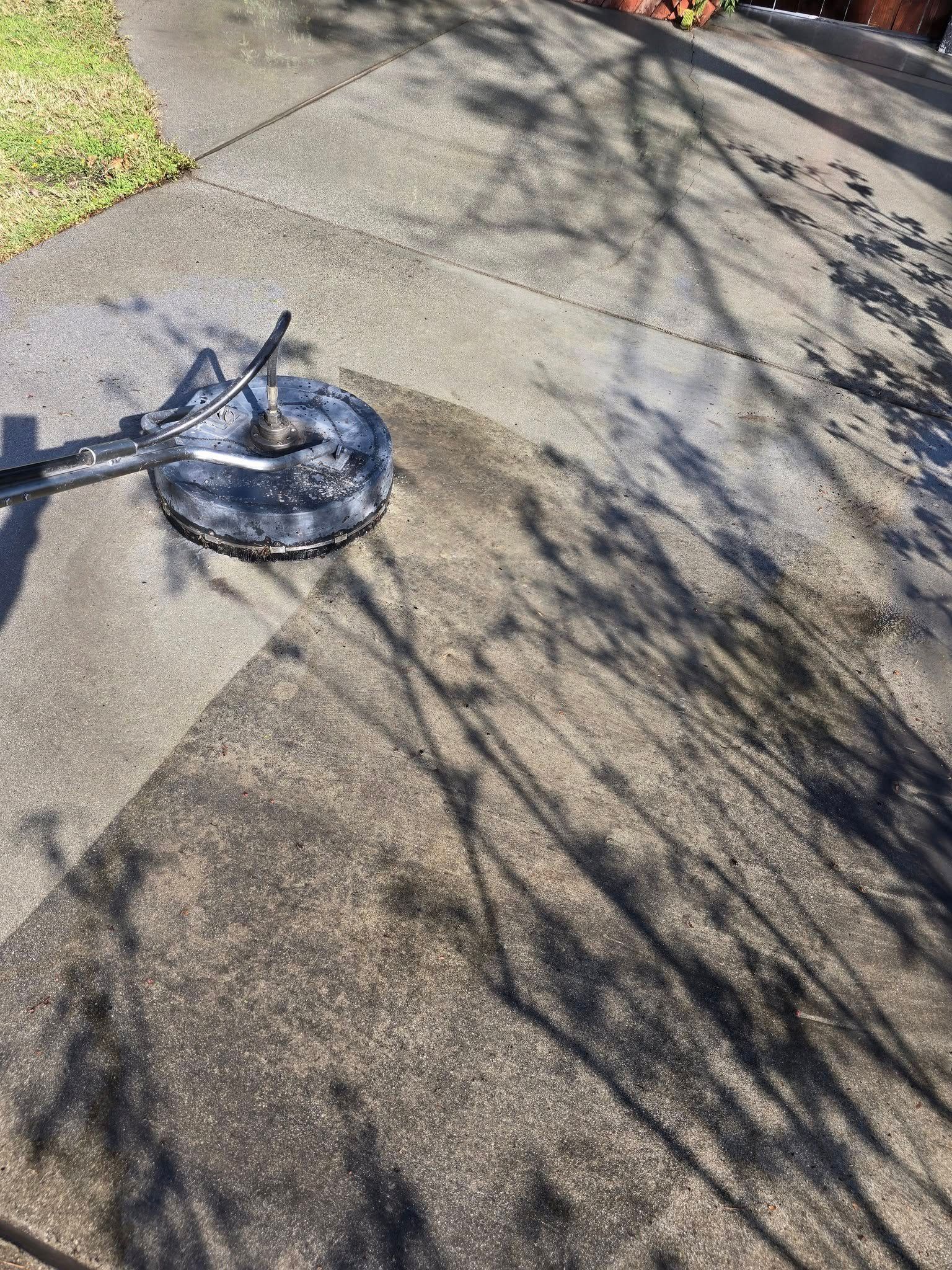 A concrete sidewalk is being cleaned with a pressure washer.
