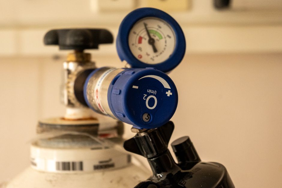 Regulador de presión azul con manómetro conectado a la válvula de una bombona de gas.