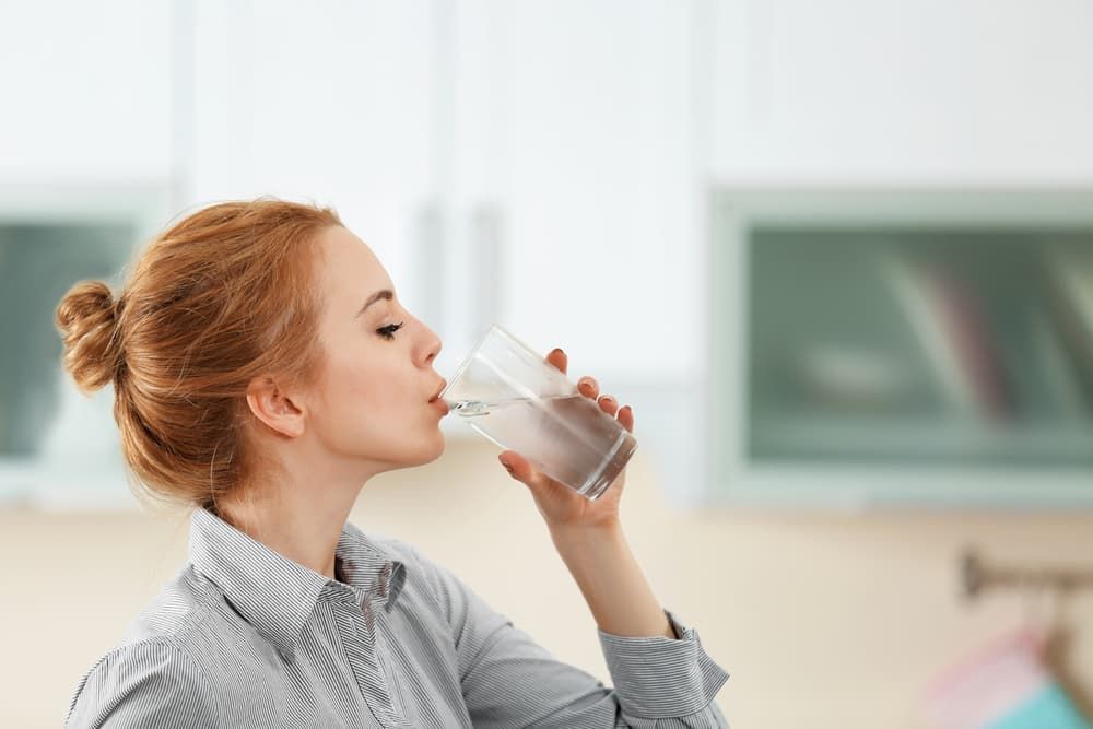 A Woman Is Drinking A Glass Of Water In A Kitchen — Billabong Springs in Sunshine Coast, QLD