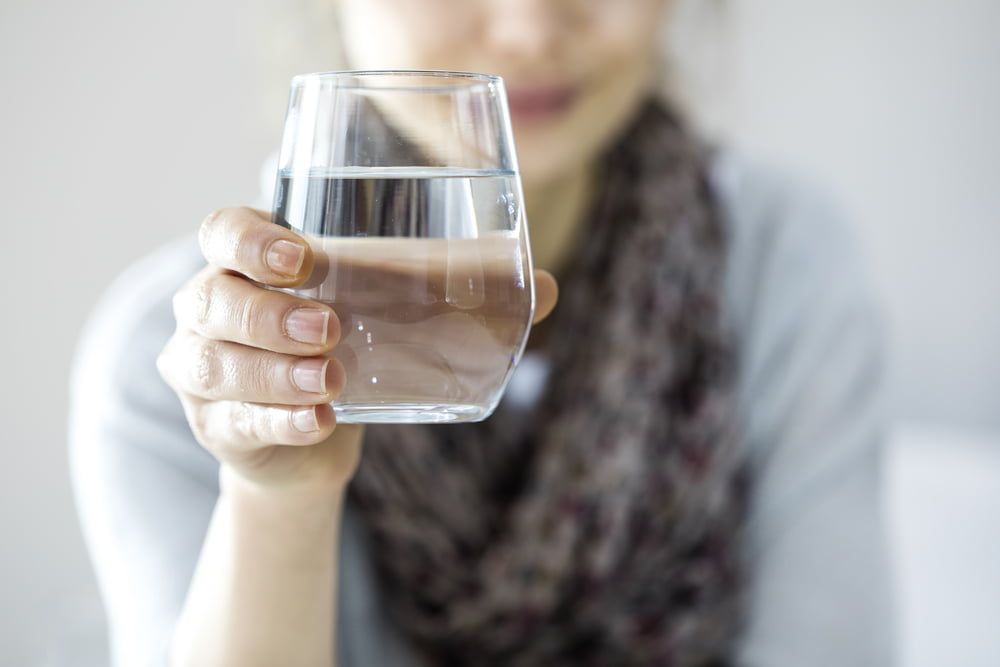 A Woman Holding A Glass Of Water In Her Hand — Billabong Springs in Toowoomba, QLD