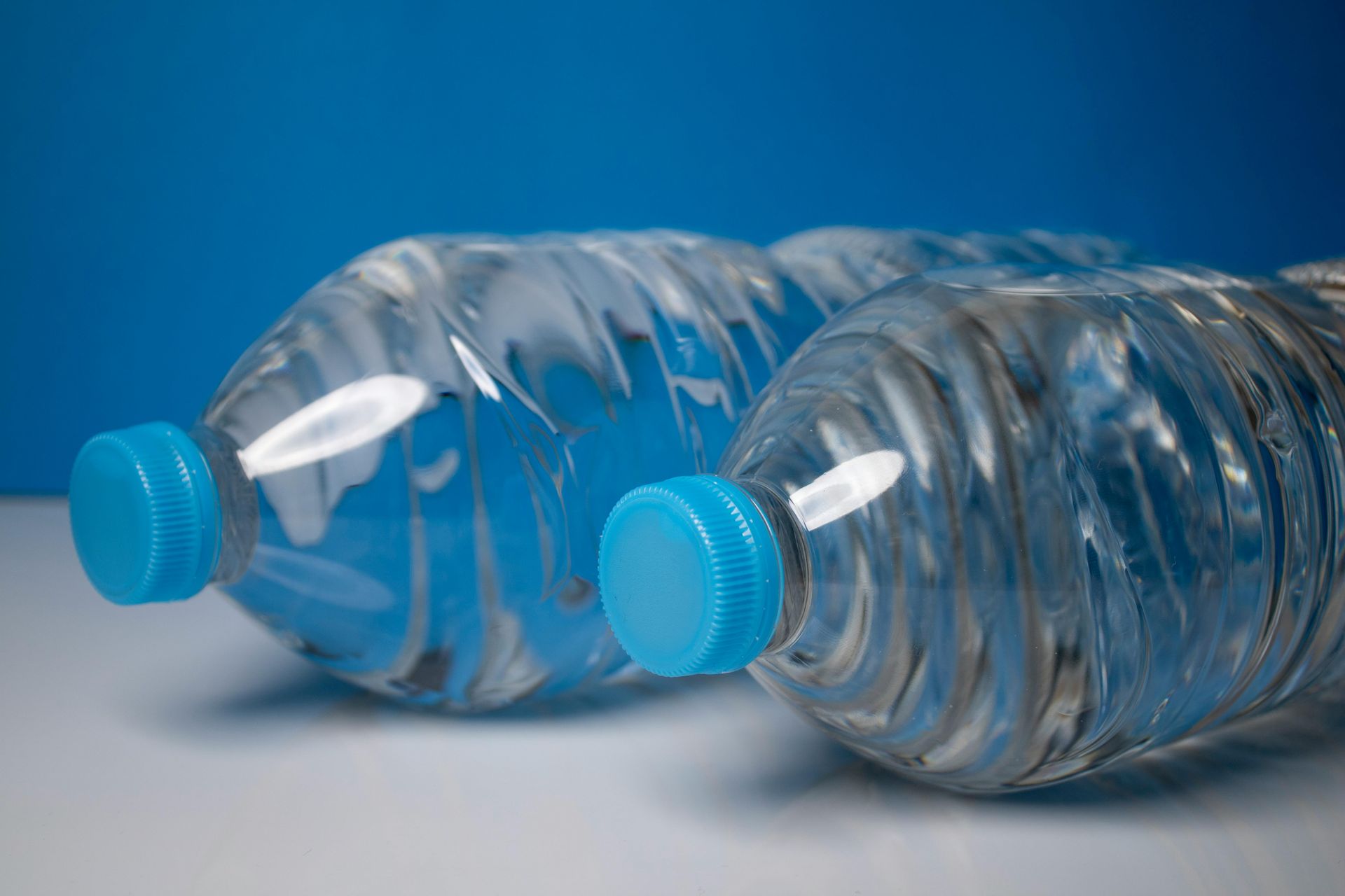 Two Plastic Water Bottles With Blue Caps On A Table — Billabong Springs in Toowoomba, QLD
