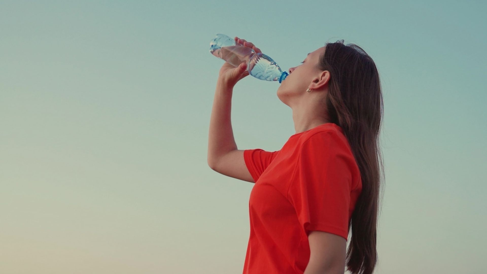 A Woman in A Red Shirt Is Drinking Water from A Plastic Bottle — Billabong Springs in Gold Coast, QLD
