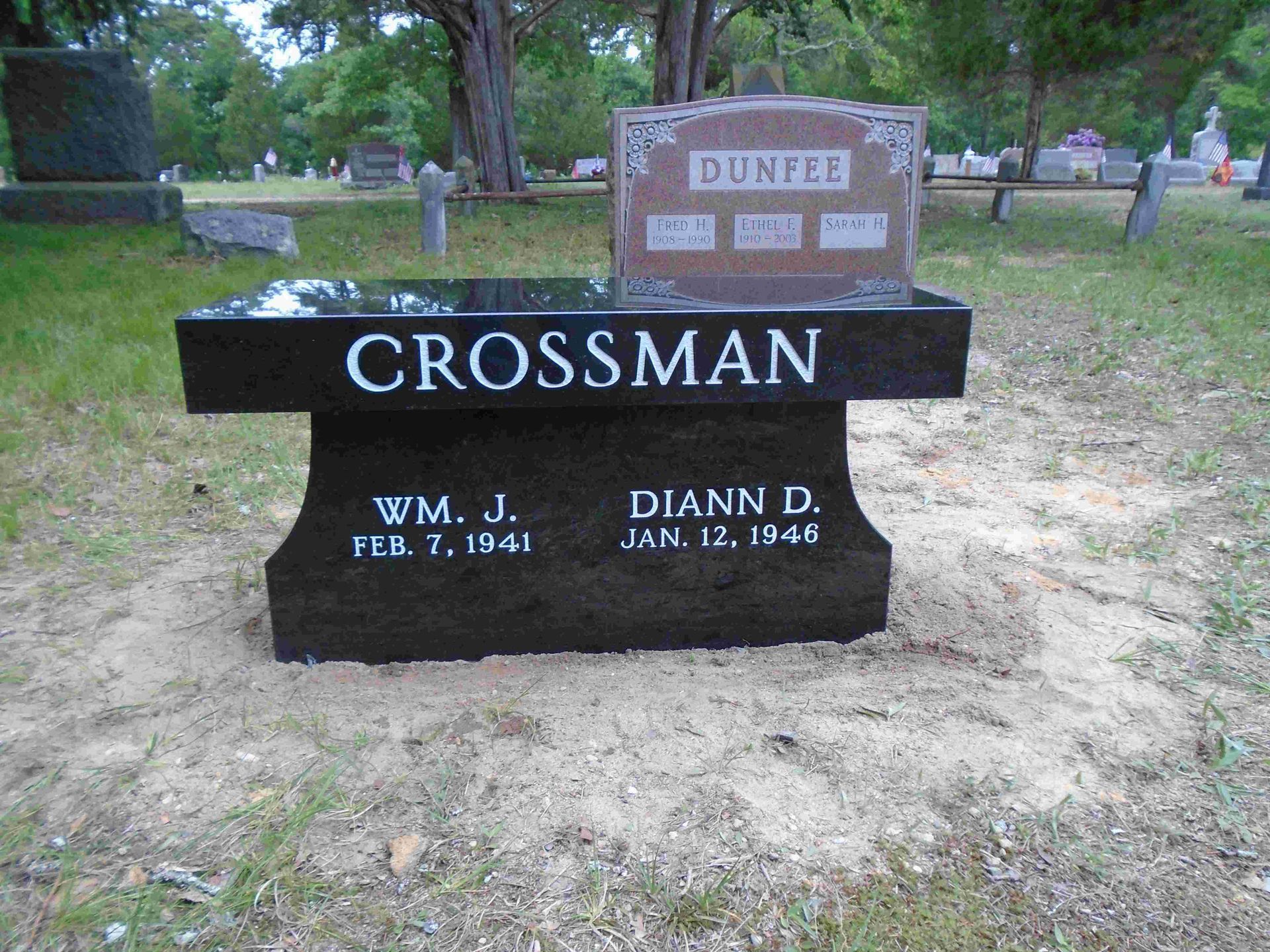 A black granite bench-style gravestone engraved