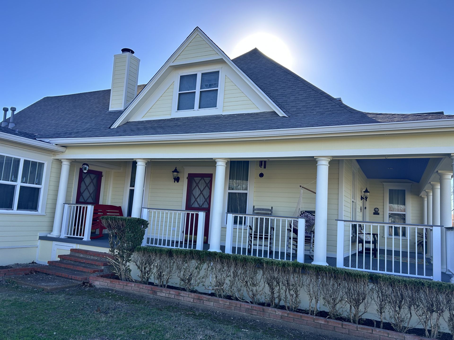 Yellow house with a front porch and sun in the background.