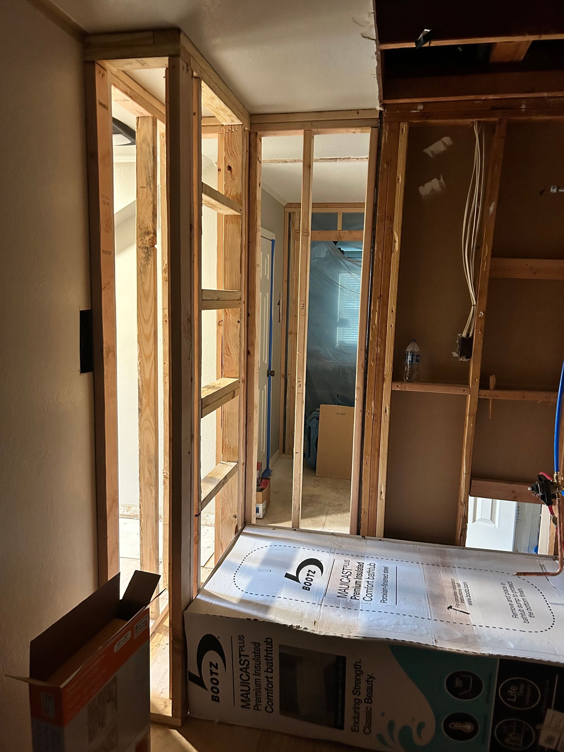 Interior construction: wooden studs frame walls and shelves, hallway visible.