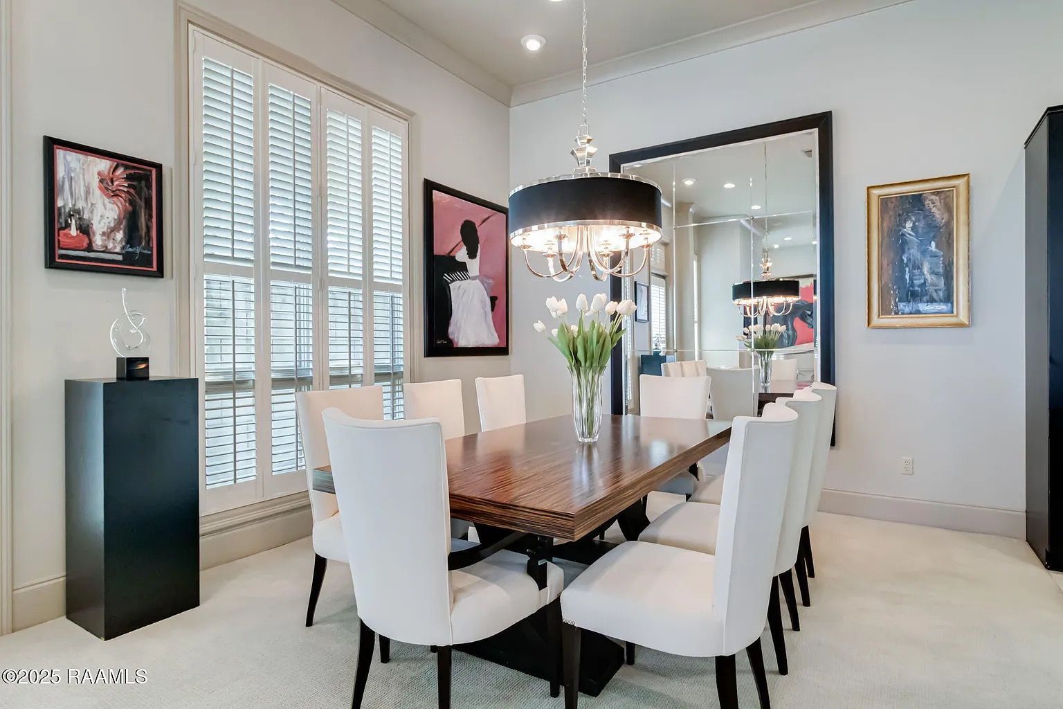 A dining room with a table and chairs and a large mirror.
