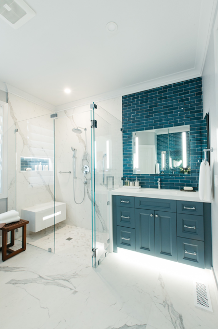 A bathroom with blue cabinets and a walk in shower