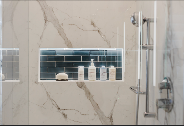 A bathroom with a shower and a shelf with bottles on it