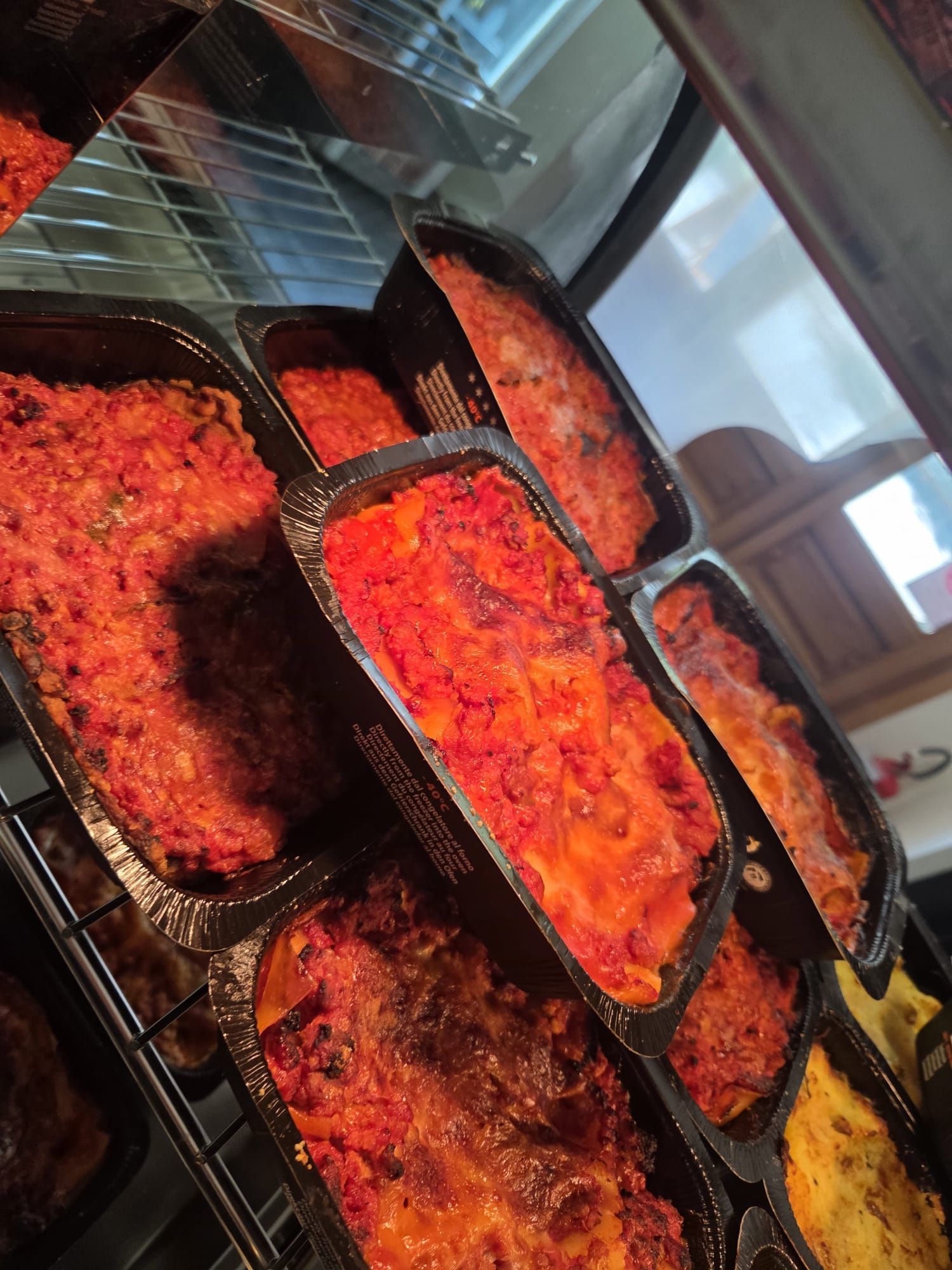 Vassoi di cibo cotto dai colori vivaci, rosso e giallo, esposti in una bancarella del mercato.