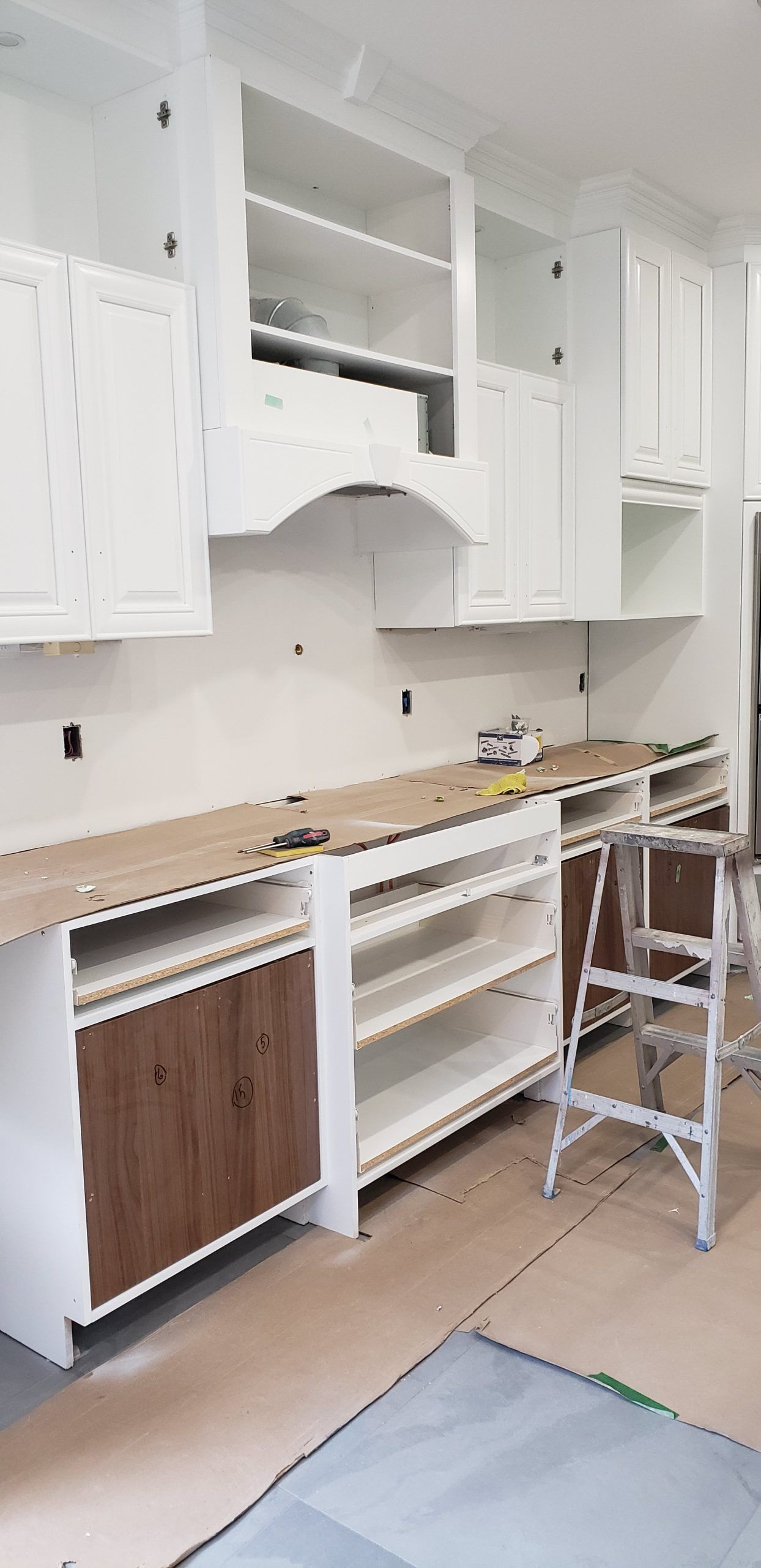 Une cuisine en construction avec des armoires blanches et des comptoirs en bois.
