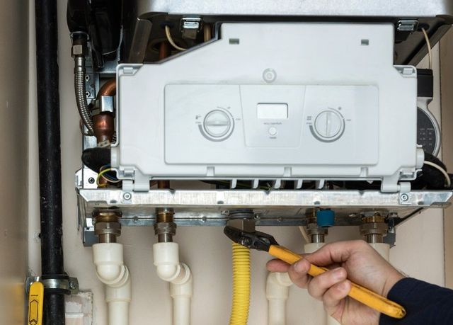 Spanner on the pipework beneath an open wall-mounted boiler