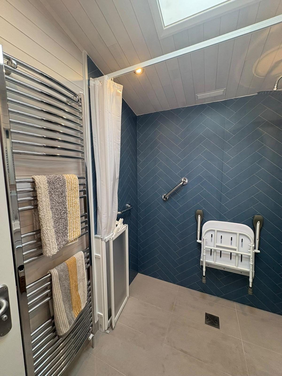 Level-access wet room with a fold-down shower seat, grab rail and herringbone wall boards