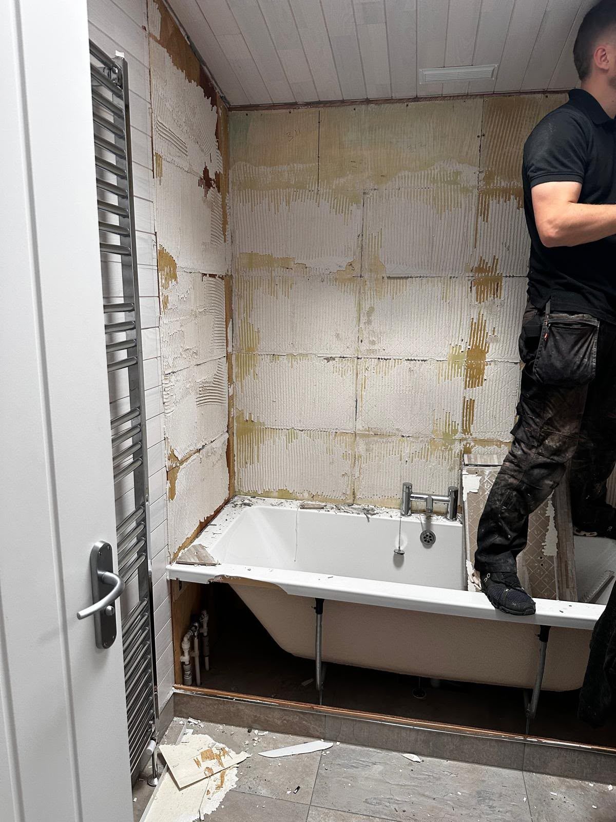 The Willington bathroom during strip-out, with the old wall tiles removed around the bath