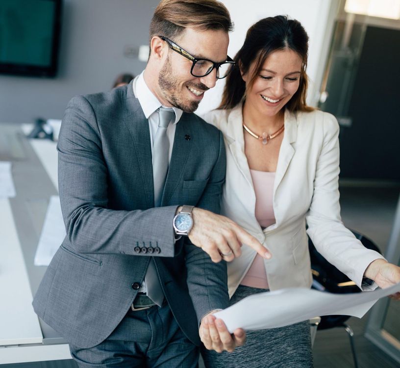 Two professionals in suits reviewing documents together in an office