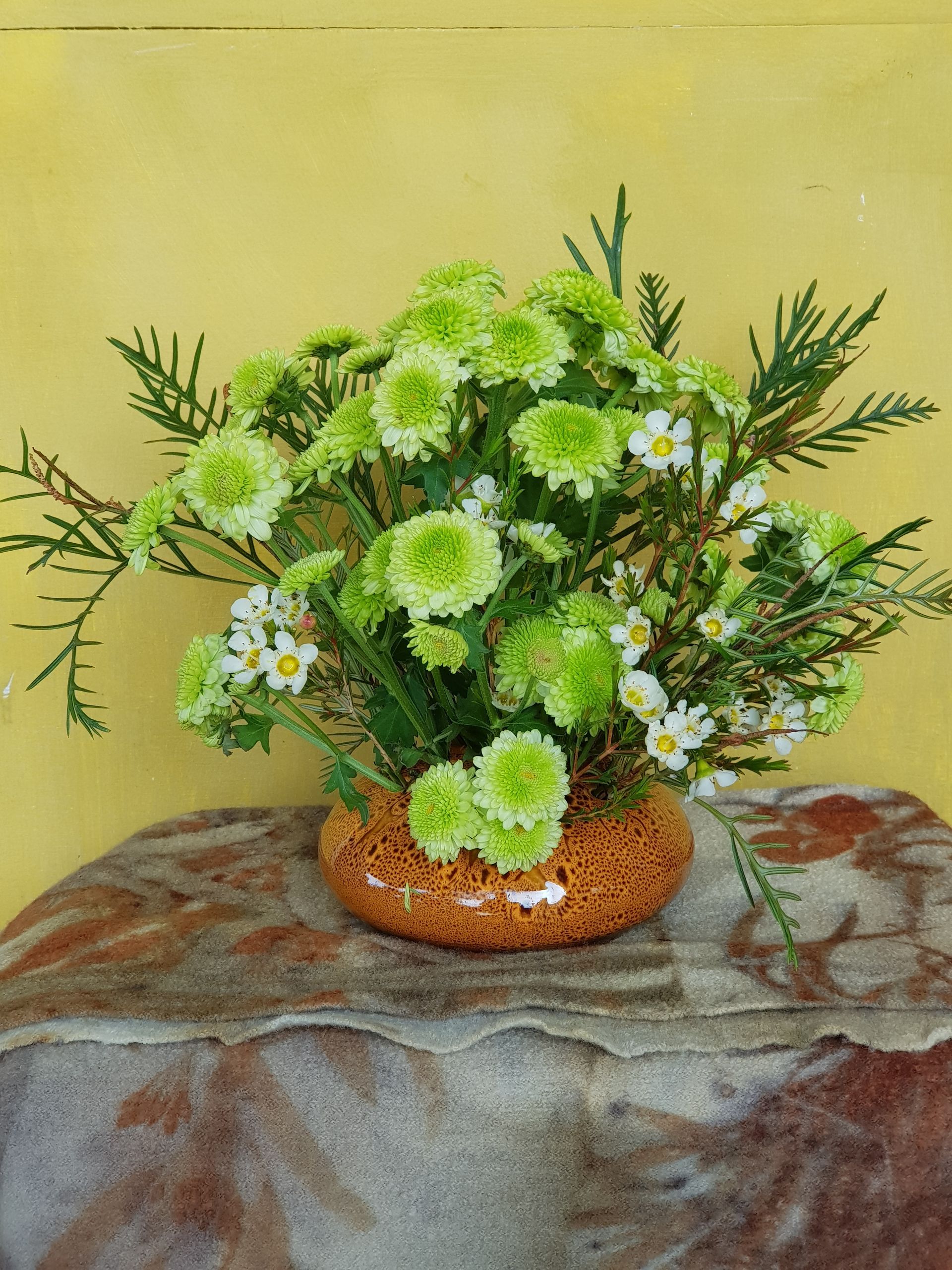 A PoseyPot filled with green and white flowers is sitting on a table.