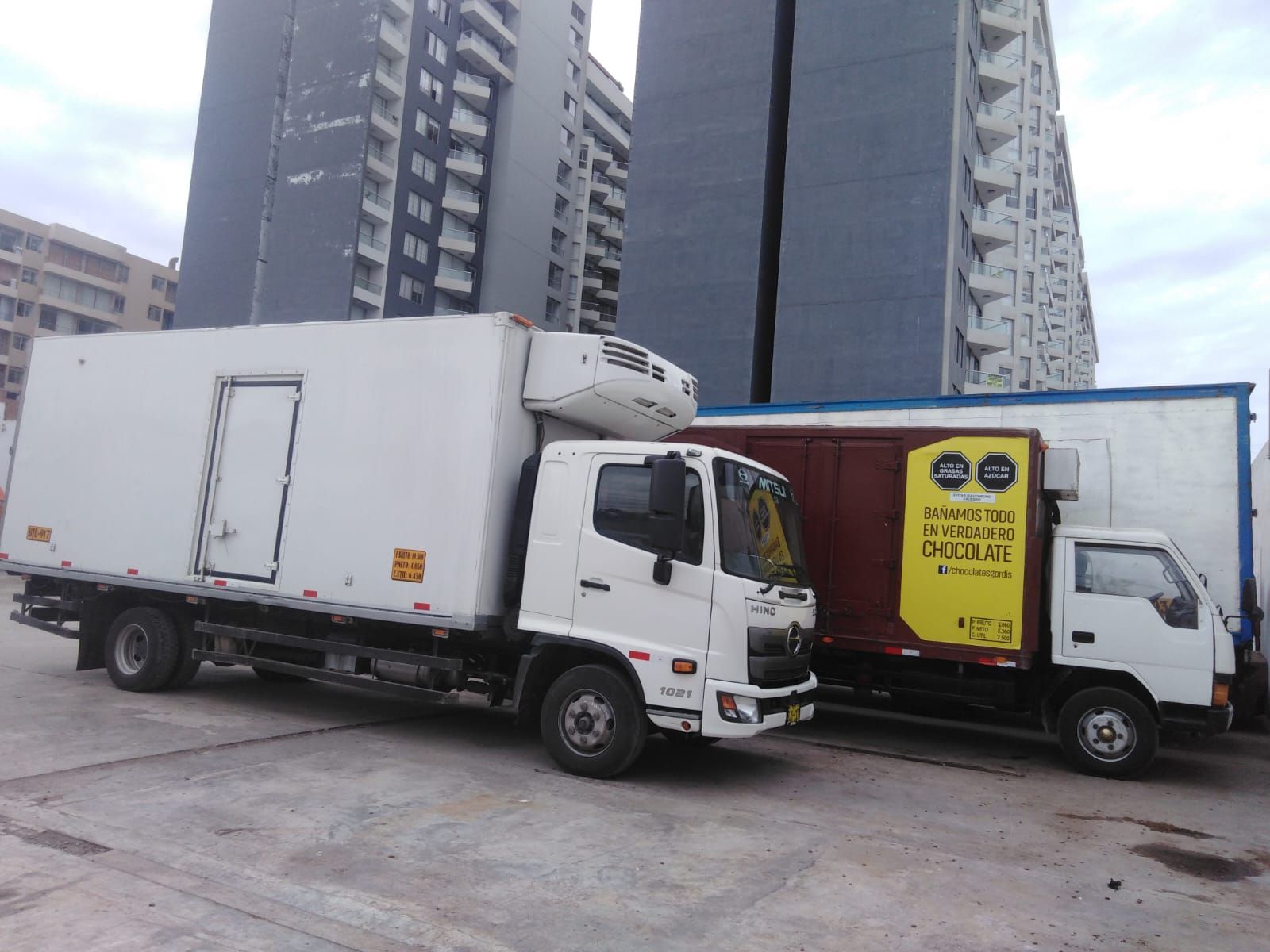 Trabajadores con chalecos amarillos descargando cajas de un camión de reparto en una calle de la ciudad.