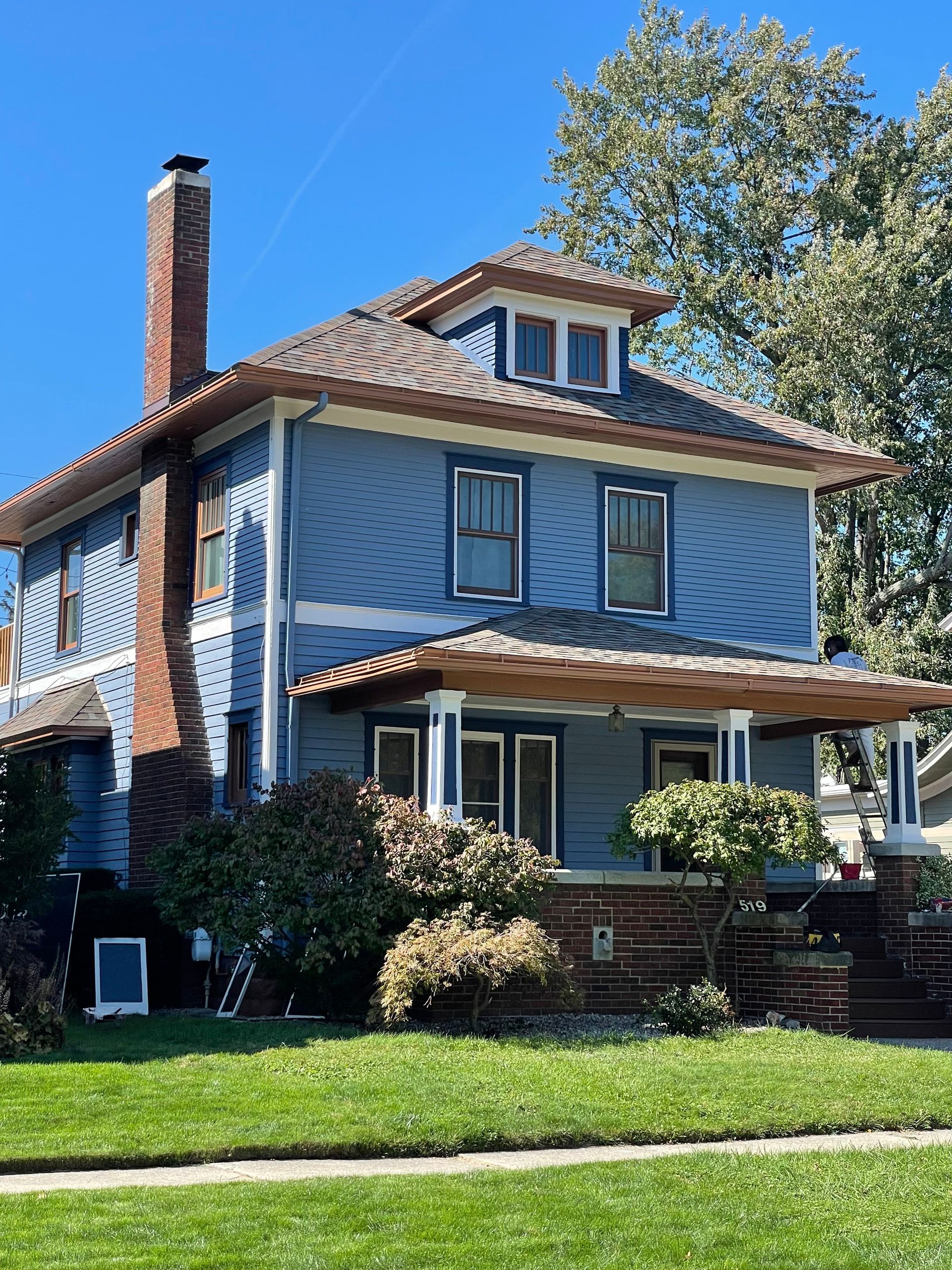 Blue house with porch and brick chimney.