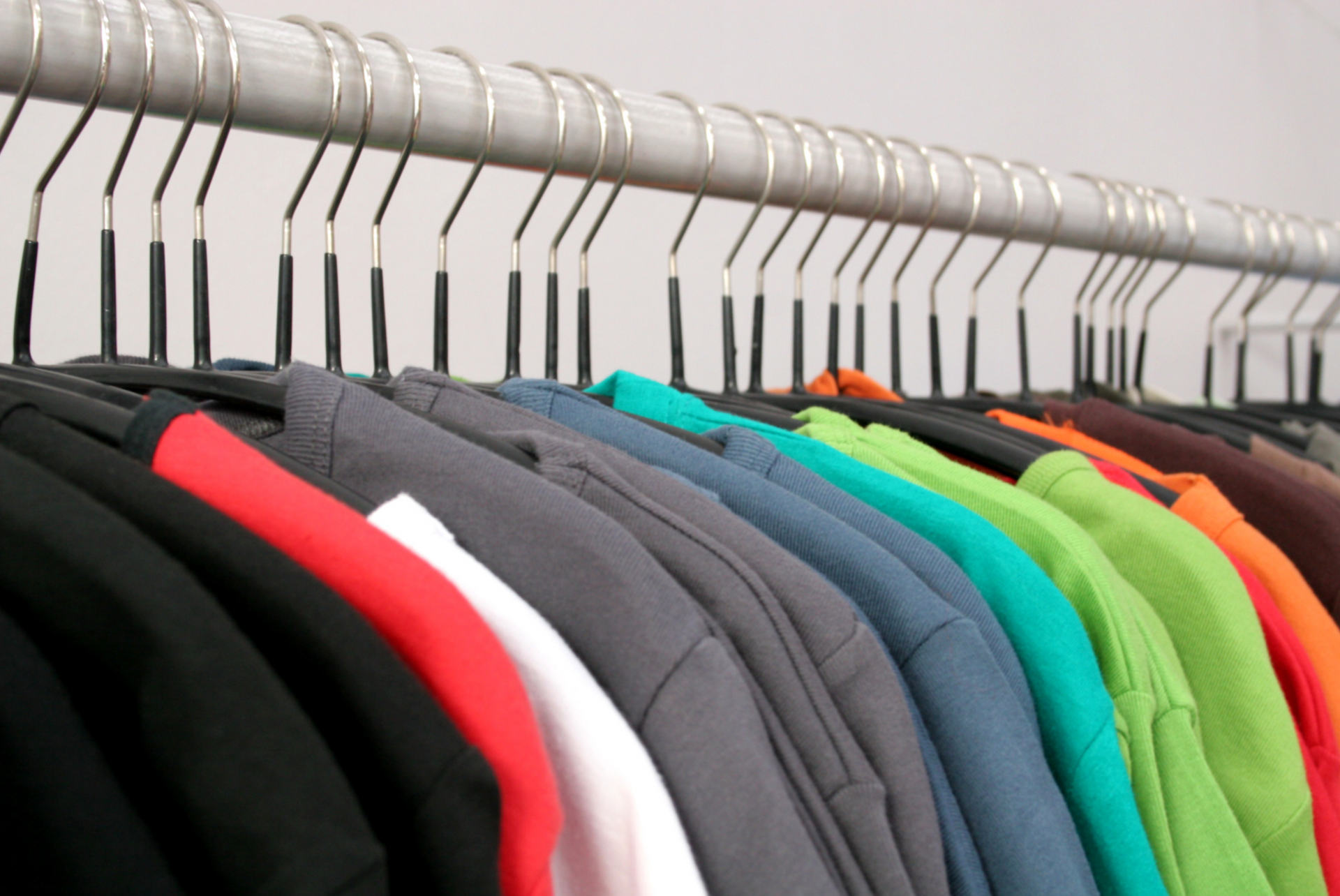 variety of t-shirts in different colors hanging on a rack