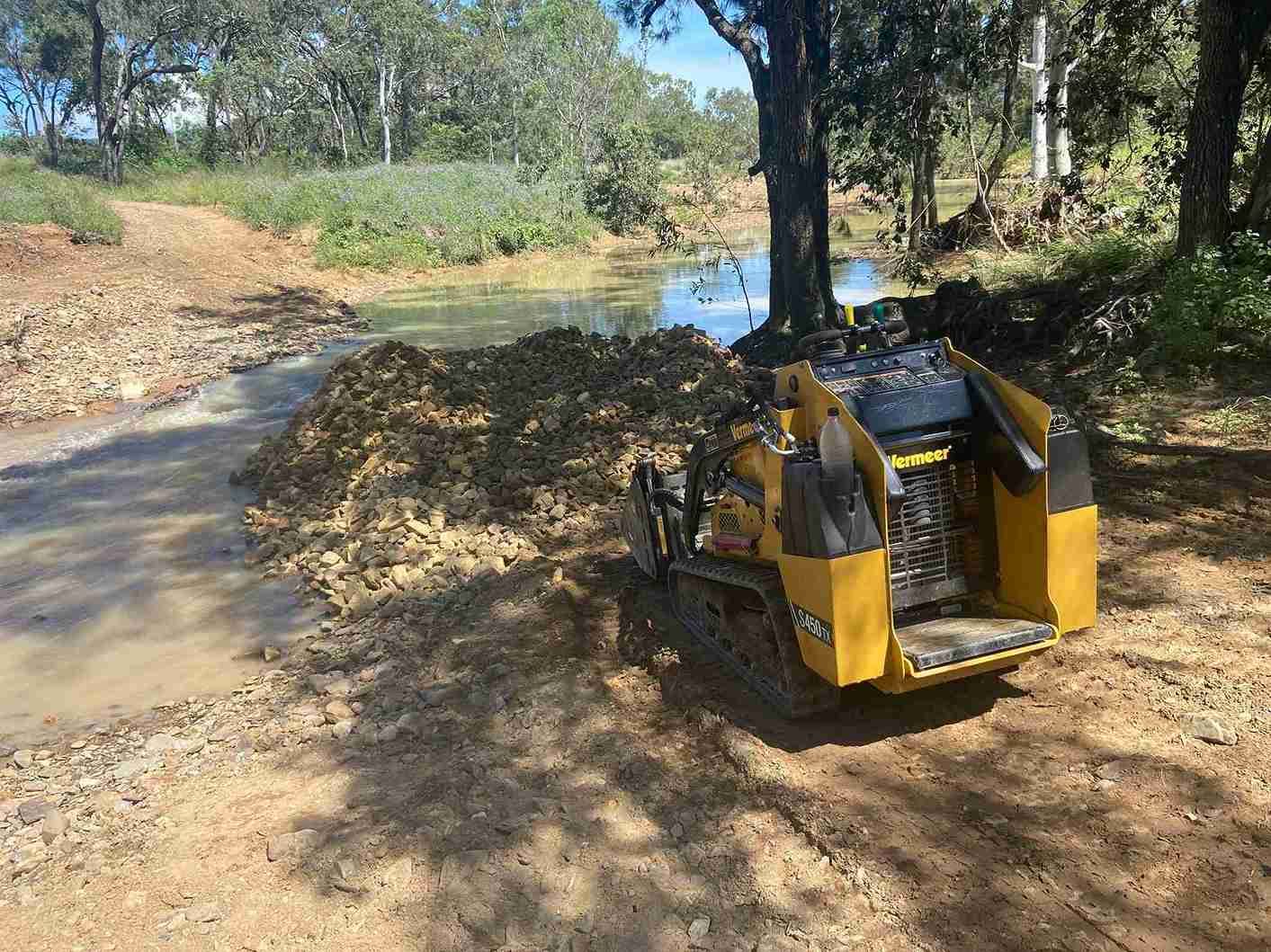 Skid Steer Loader Parked Beside a River — RCJJ Mini Loaders In Mareeba, QLD