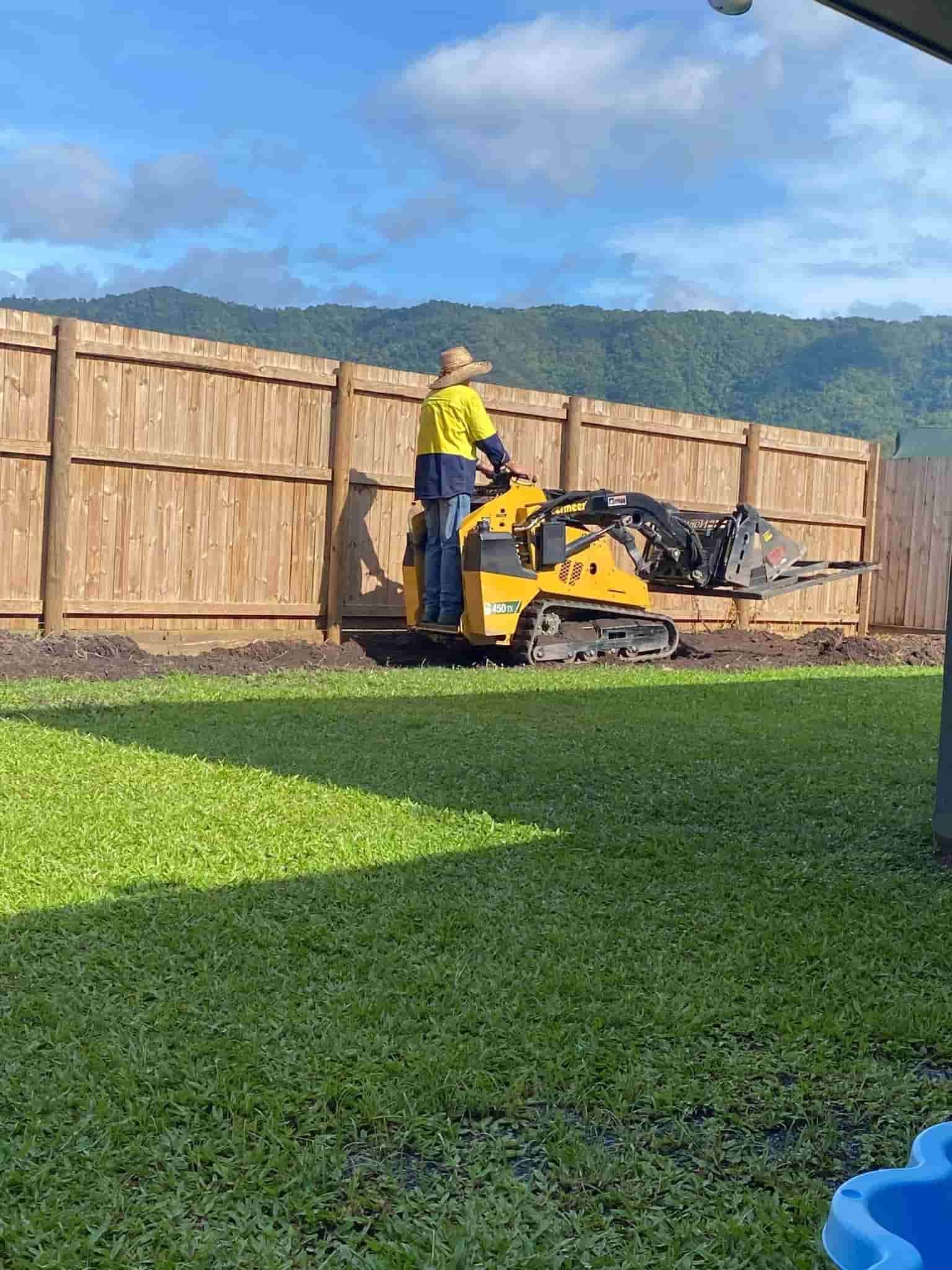 A Man is Riding a Bulldozer on a Lush Green Lawn — RCJJ Mini Loaders In Mareeba, QLD