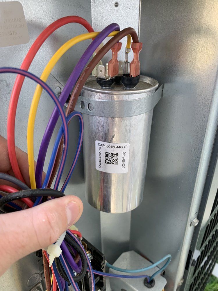 A person is holding a capacitor next to a bunch of wires.
