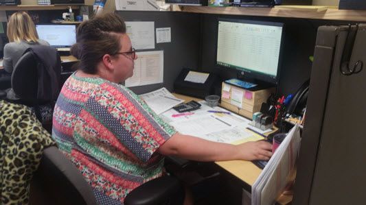 A woman is sitting at a desk in front of a computer.