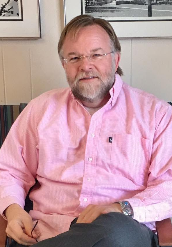 A man with a beard and glasses is wearing a blue shirt.