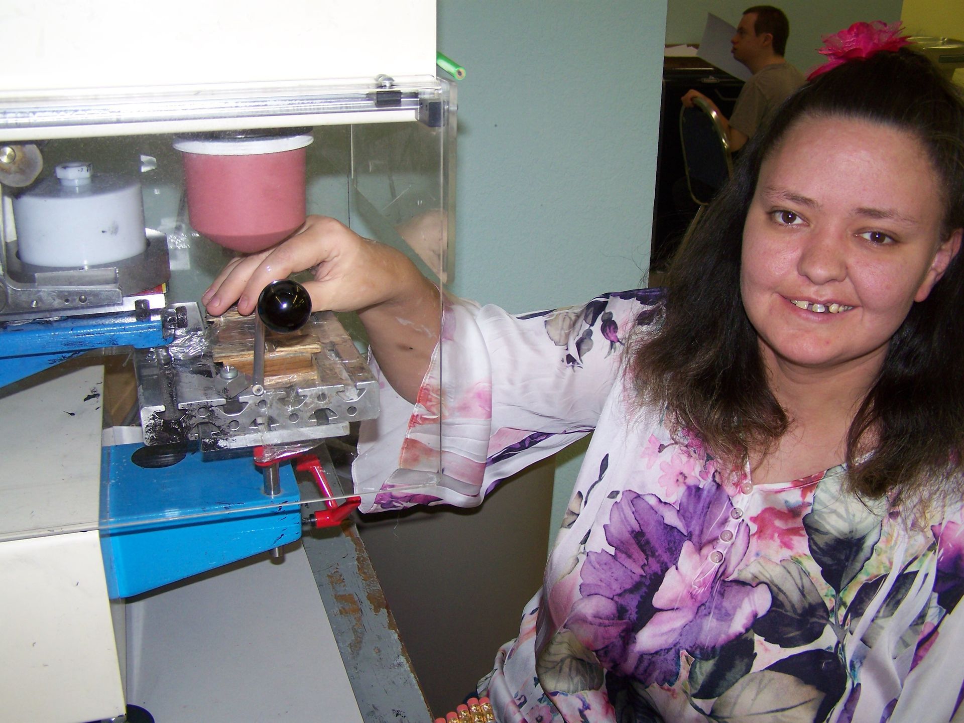 A woman in a floral shirt is using a machine