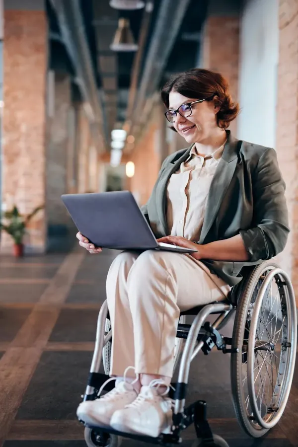 A woman in a wheelchair is using a laptop computer.
