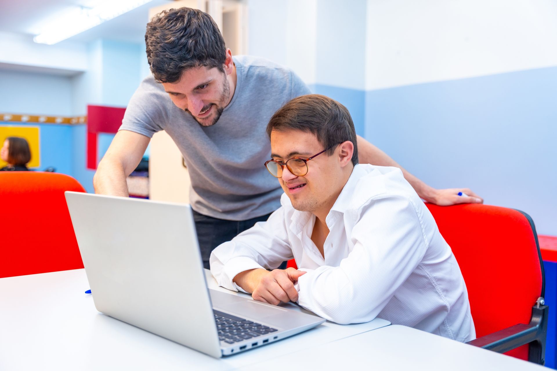 Two men are looking at a laptop computer together.