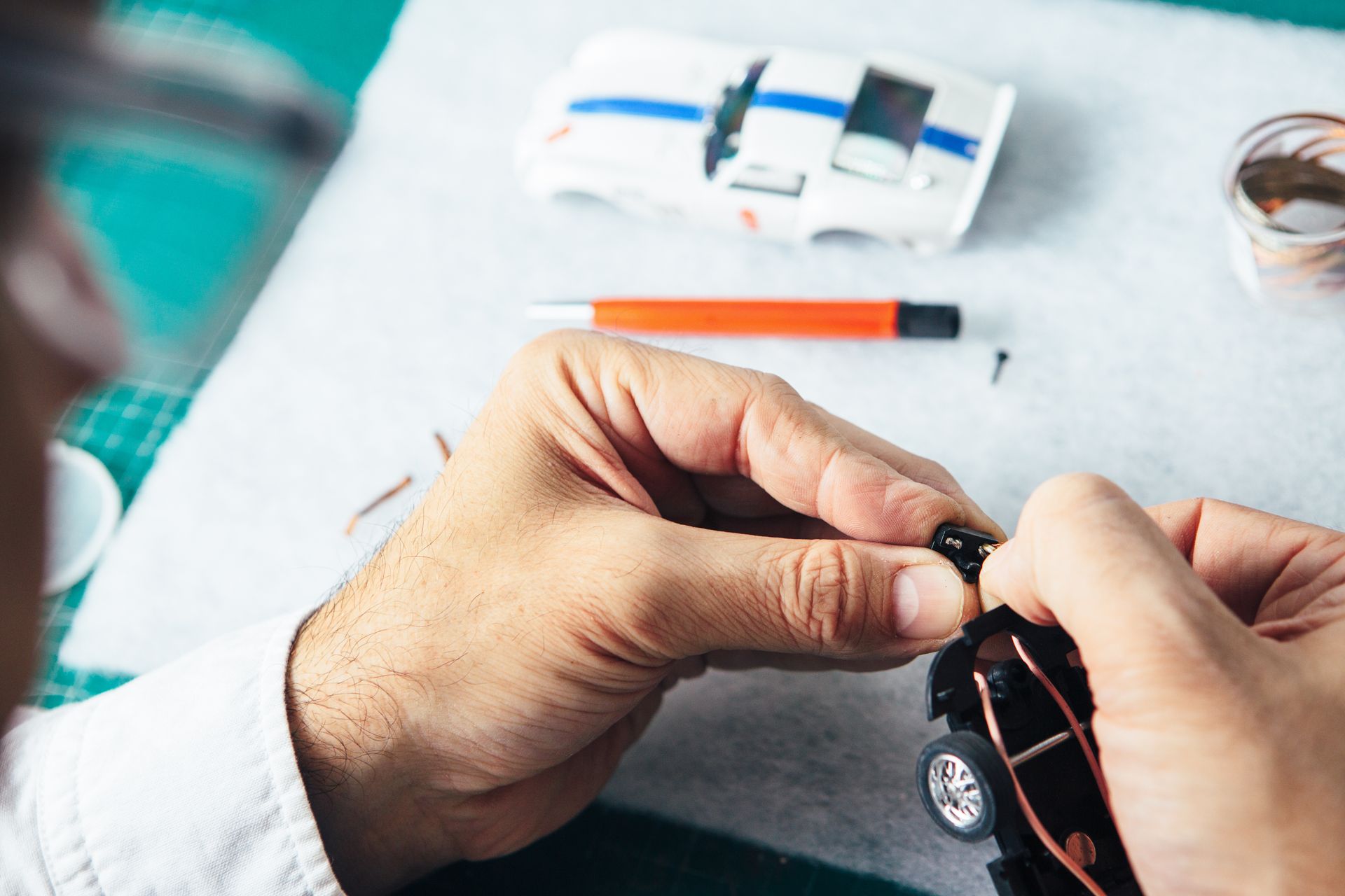 A person is working on a toy car on a table.