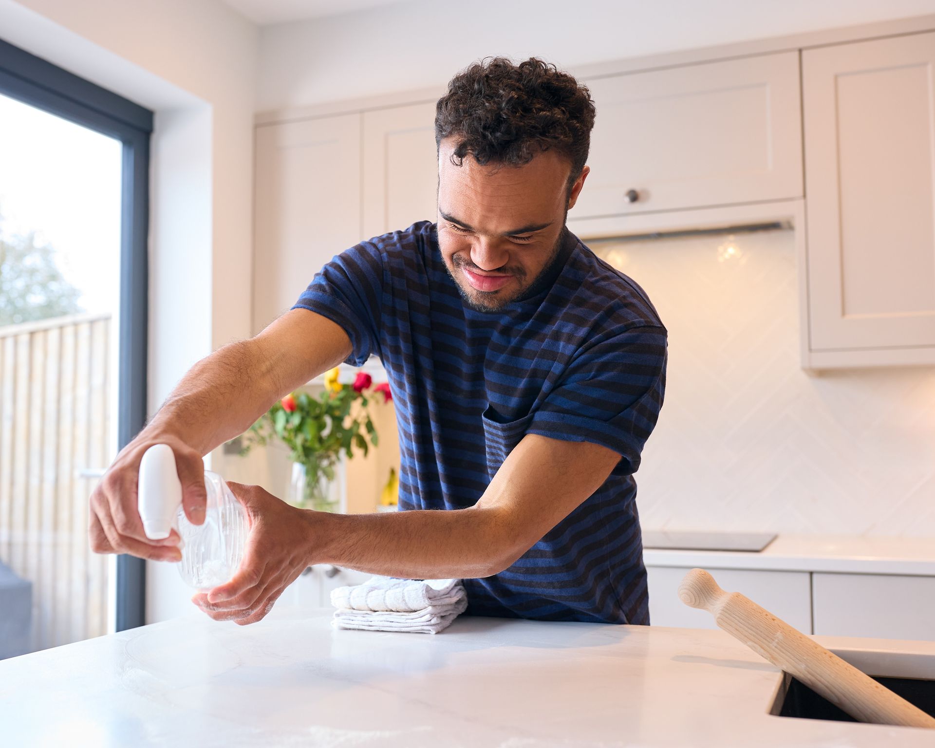 A man is cracking an egg on a counter in a kitchen.