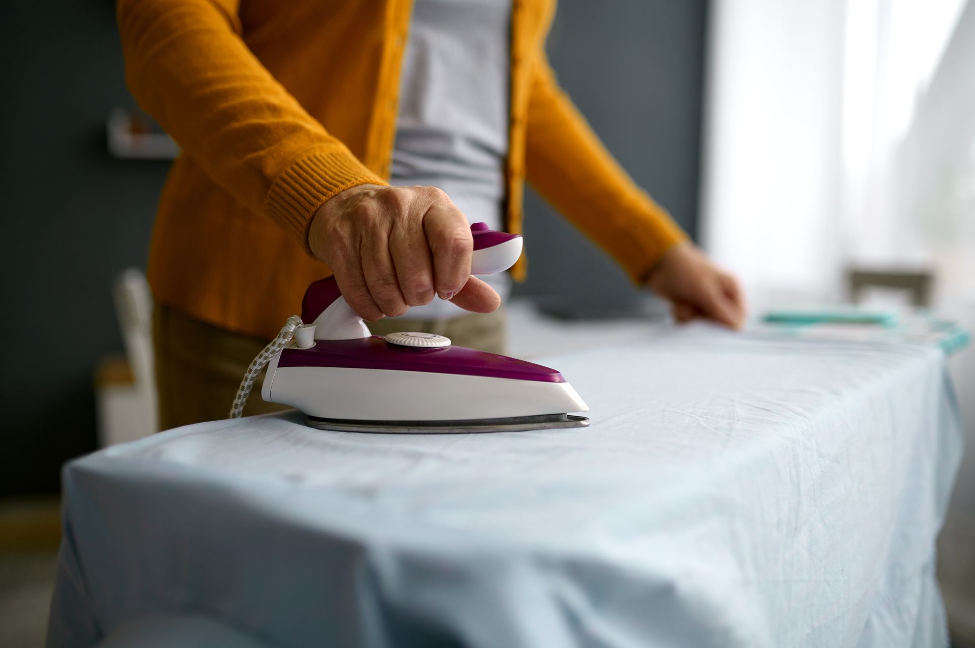 A woman is ironing a piece of cloth on an ironing board.