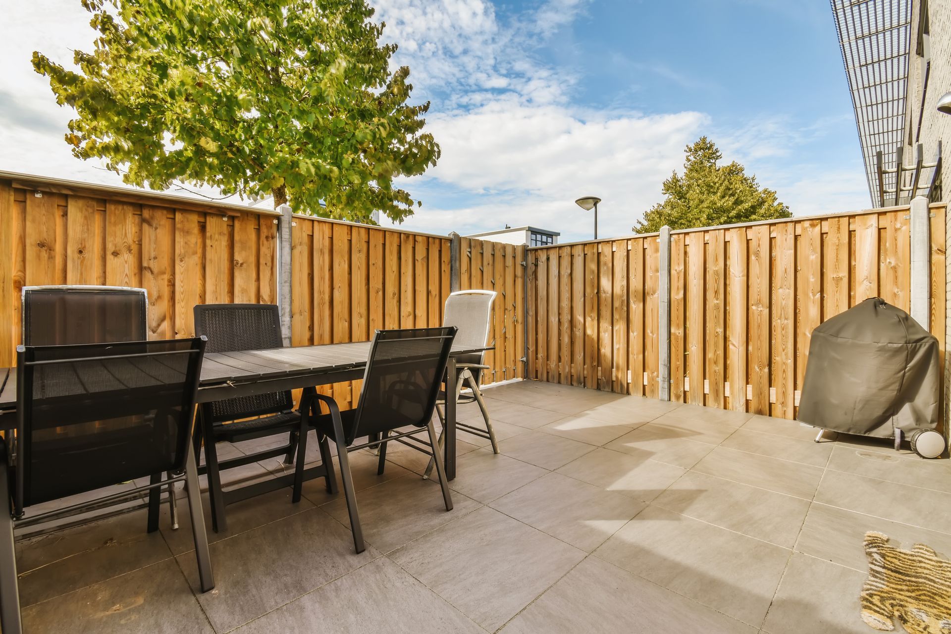 A patio with a table and chairs and a wooden fence.
