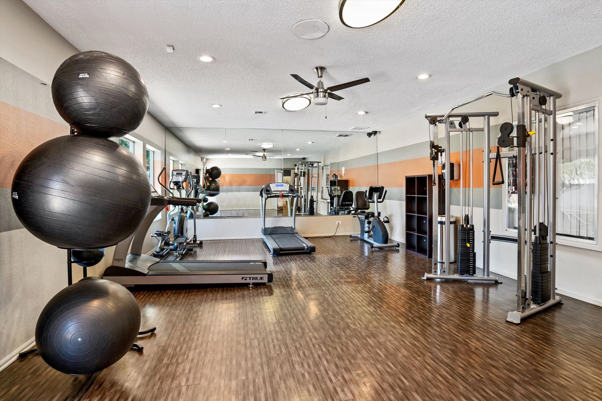 Gym interior with exercise equipment: treadmills, weights, and stability balls.